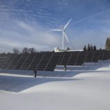 Photovoltaikanlagen im Winter mit Windenergieanlage im Hintergrund